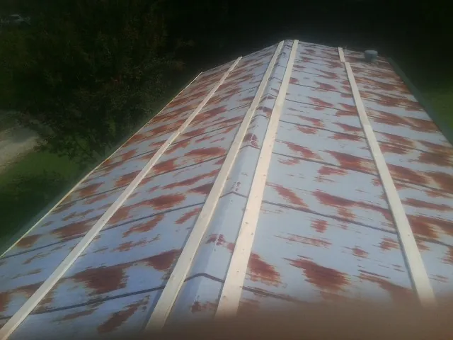 Rusted metal roof panels with new wood purlins before replacement — Storm Damage Roof Repair in Gowen by Roofing Brothers