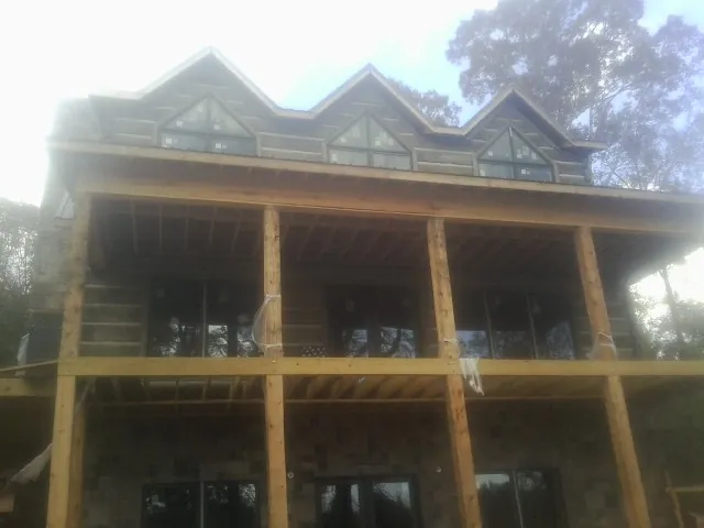 Dormers and porch framing on a large log home under construction — Roof Coating work by our crew in Gowen