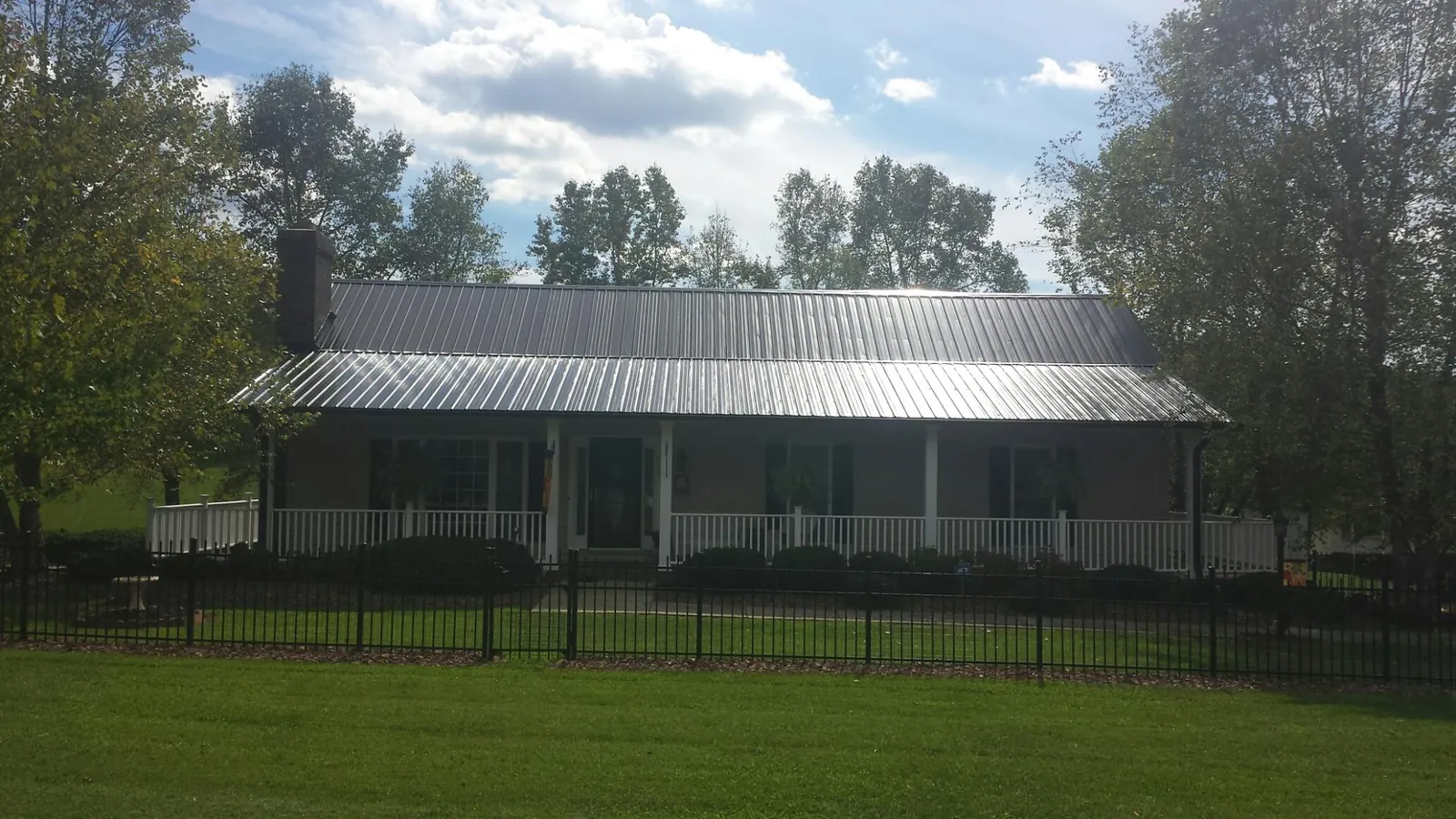 Gray metal roof on a brick ranch with a full width front porch — Gutter Guard Installation work by our crew in Gowen