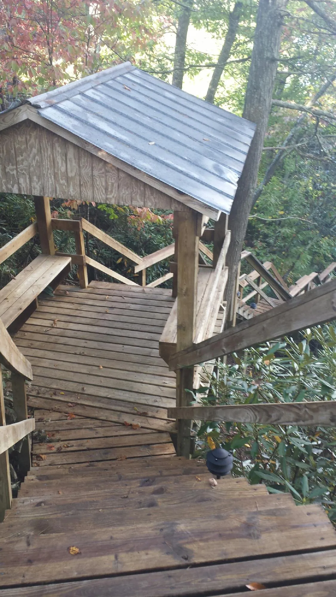 Metal roofed shelter over wooden steps on a wooded walkway — Skylight Repair & Installation work by our crew in Gowen