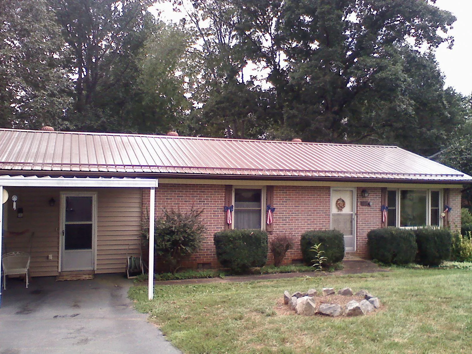 Bronze metal roof and carport on a brick ranch home — Roof Repair work by our crew in Gowen