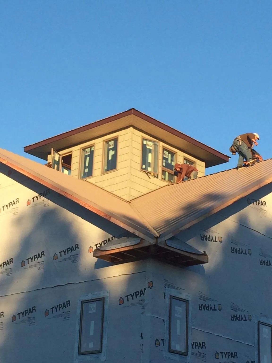 Roofers working around a rooftop cupola on a new metal roof at sunset — Roof Waterproofing in Gowen by Roofing Brothers